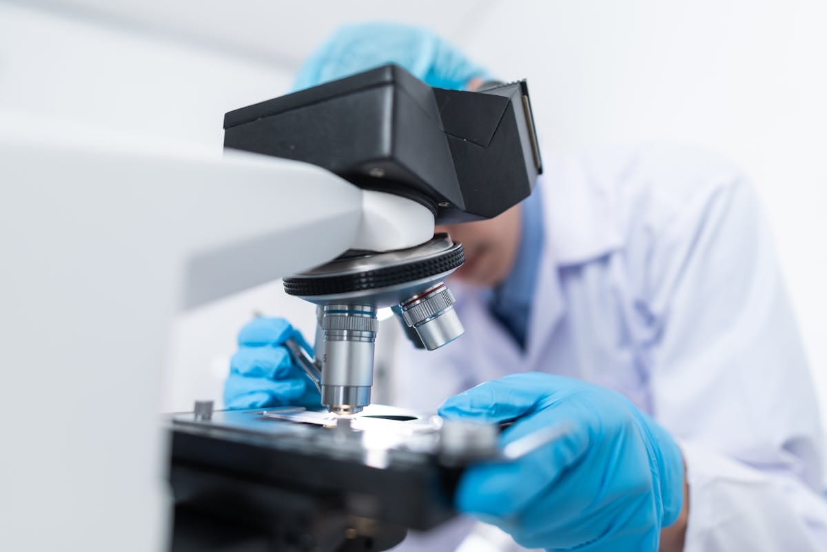 Scienziato che esamina campioni al microscopio in un laboratorio di ricerca nanotecnologica